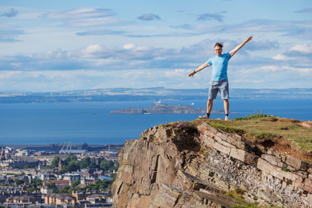 Explorer on cliff top, enjoying stunning ocean vista of Edinburghの写真素材
