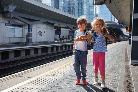 Two kids joyfully explore urban station together wait for trainの写真素材