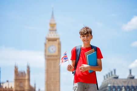 Young student boy in London city holding books and British flagの写真素材