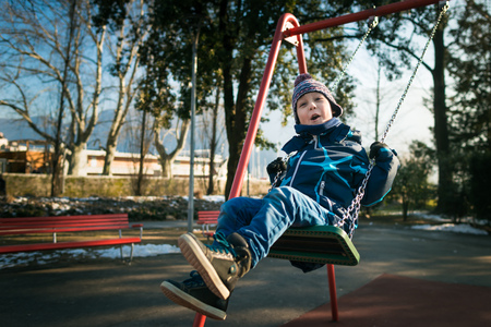 Happy little boy on the beach. One person. Swinging on the swing in the playground areaの写真素材