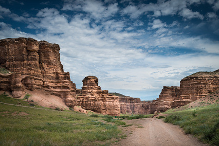 Scenic landscape inside canyon with long country road. Rocks on sides. Cloudy dramatic sky.の写真素材