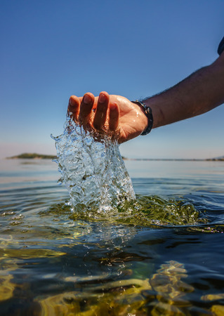 Man's hand in the sea. Water and drop splashing. Hand, sea, reflection.の写真素材