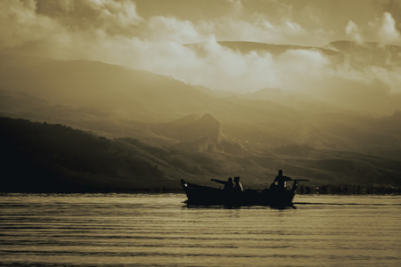 Sunset landscape with lake, boat, mountains and dramatic clouds from Iznik (Nicaea), Bursa, Turkey.