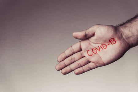 Covid-19 text written on hand of man. Covid-19, Coronavirus, SARS-CoV-2 outbreak. 2019 Novel Coronavirus concept and background.の写真素材