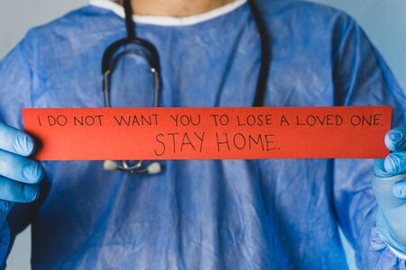 The doctor gives the stay home message with red paper in his hand.の写真素材