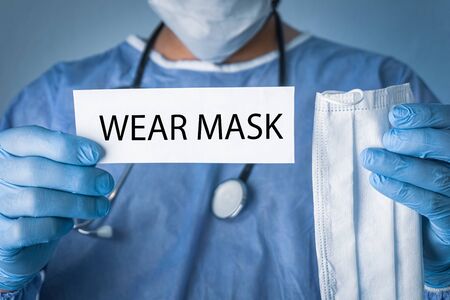 Conceptual photo for COVID-19 epidemic. Doctor holding a white paper that written wear mask.