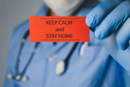 Coronavirus concept. Doctor holding a red paper that written Stay home.の写真素材