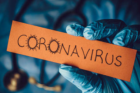 Concept of Covid-19 pandemic.Doctor holding a paper that written coronavirus.の写真素材