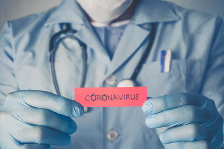 Concept of Covid-19 pandemic. Doctor holding a red paper that written coronavirus.の写真素材
