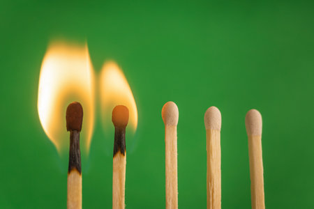 Two burnt match in set of matchsticks on green background. selective focus.の写真素材