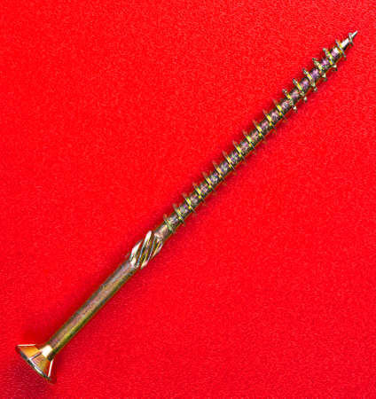 a screw isolated on red backgroundの写真素材