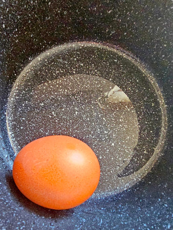 Egg in a bowl on a black background. Top view.