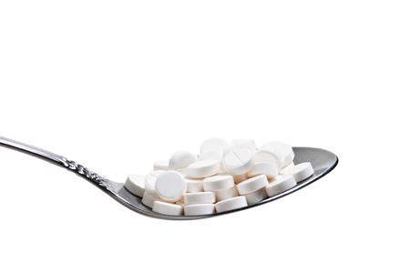 pills in a spoon isolated on white backgroundの写真素材