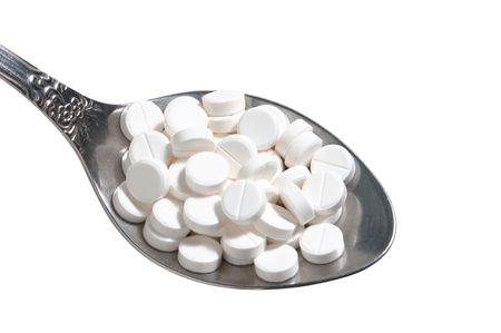 pills in a spoon isolated on white backgroundの写真素材