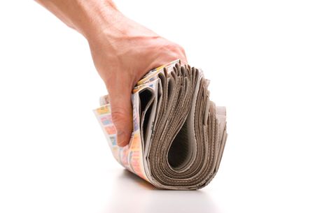 hand holds a bundle of newspapers isolated on a white backgroundの写真素材