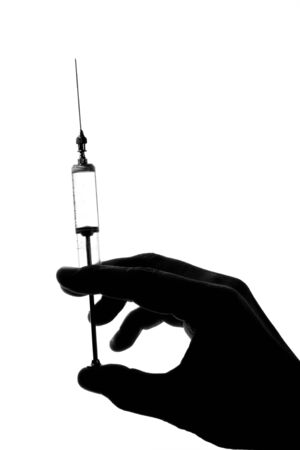 Silhouette old glass syringe in hand isolated on whiteの写真素材