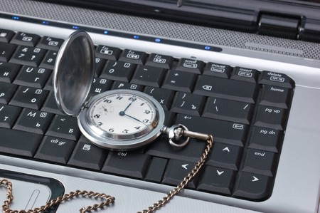 pocket watch on a laptop keyboardの写真素材