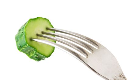 fresh green cucumber at the fork isolated on whiteの写真素材