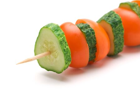 slices of cucumbers and tomatoes on a wooden stick  isolated on white backgroundの写真素材