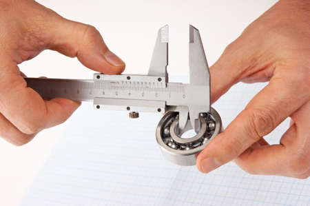callipers with  bearing in hand on a background of graph paperの写真素材