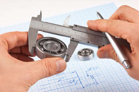 Technical drawing and callipers with bearing in hand on graph paperの写真素材
