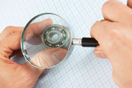 magnifying glass  in hand and  bearing on graph paperの写真素材