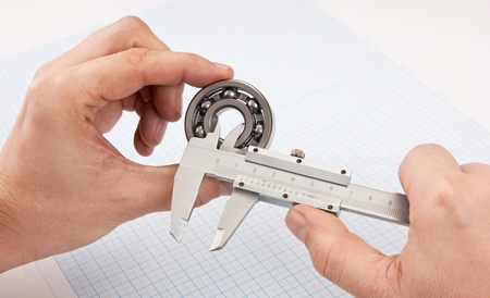 callipers with  bearing in hand on a background of graph paperの写真素材