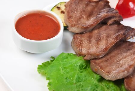 dishes of roast meat with vegetables and spicesの写真素材