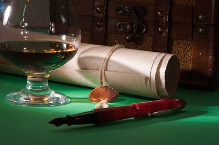 secret scroll with a wax seal and a glass of cognac on the green baizeの写真素材