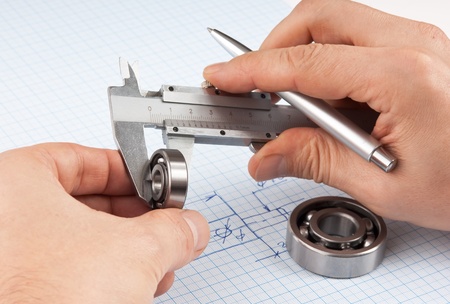 Technical drawing and callipers with bearing in hand on graph paperの写真素材