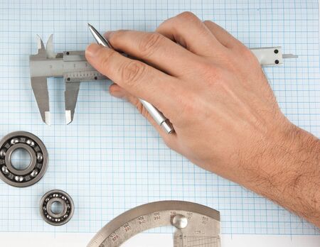 callipers in hand on graph paperの写真素材