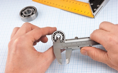 callipers with  bearing in hand on a background of graph paperの写真素材