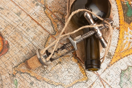 bottle of wine and a corkscrew on the background of old maps