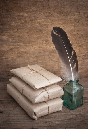 pile parcel wrapped with brown kraft paper and a quill in the inkwellの写真素材