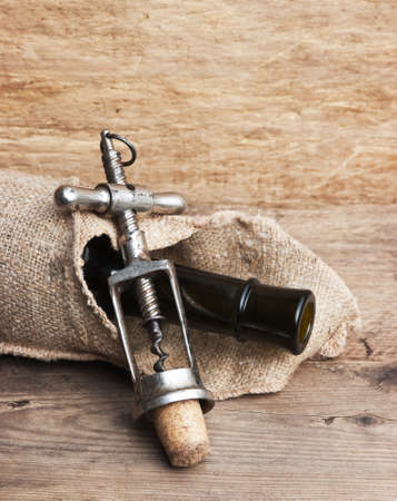 Old corkscrew and bottle of wine on the boardの写真素材