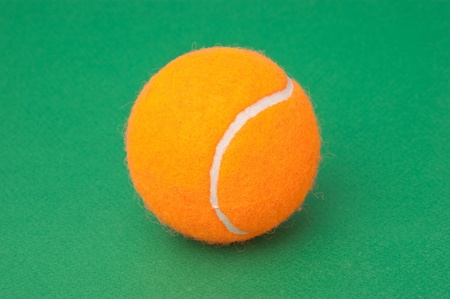orange tennis ball on a green backgroundの写真素材
