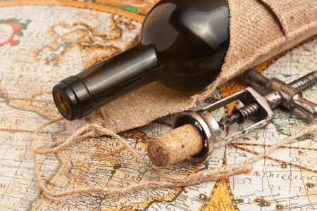 bottle of wine and a corkscrew on the background of old maps