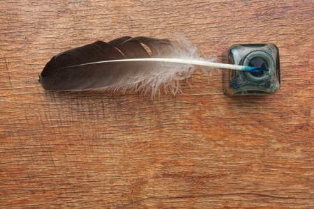 quill pen in a glass inkwell on a wooden tableの写真素材