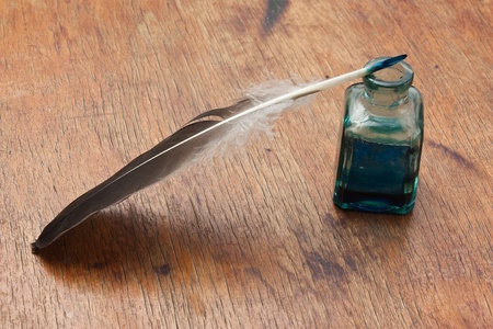 quill pen in a glass inkwell on a wooden tableの写真素材