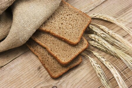 slices of rye bread and ears of corn on the wooden tableの写真素材