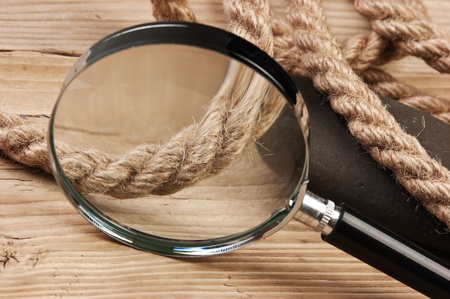 magnifying glass and rope on a wooden backgroundの写真素材