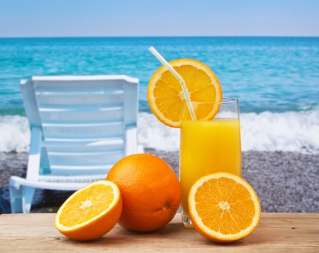 Glass of orange juice on a beach table の写真素材
