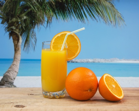 Glass of orange juice on a beach table の写真素材