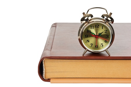 golden alarm clock on the book  isolated on a white background の写真素材