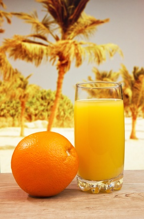 Glass of orange juice on a beach table の写真素材