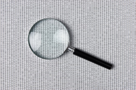 magnifying glass on the background of a binary codeの写真素材