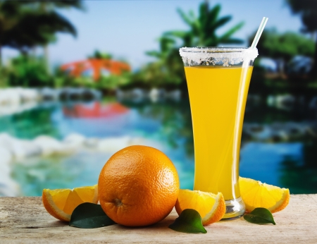 Glass of orange juice on a beach table の写真素材