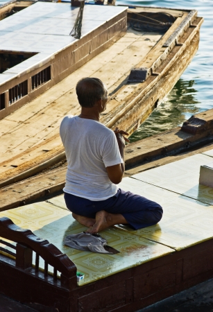 DUBAI, UAE-NOVEMBER 13: An unidentified man - boatman sitting in a boat and prays on November 13, 2012 in Dubai, UAE.のeditorial素材