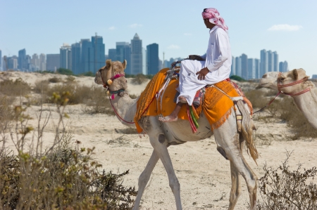 Bedouin on a camel in the desert and a modern city on the horizon