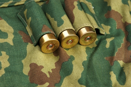 Old hunting cartridges and bandoleer on camouflage background